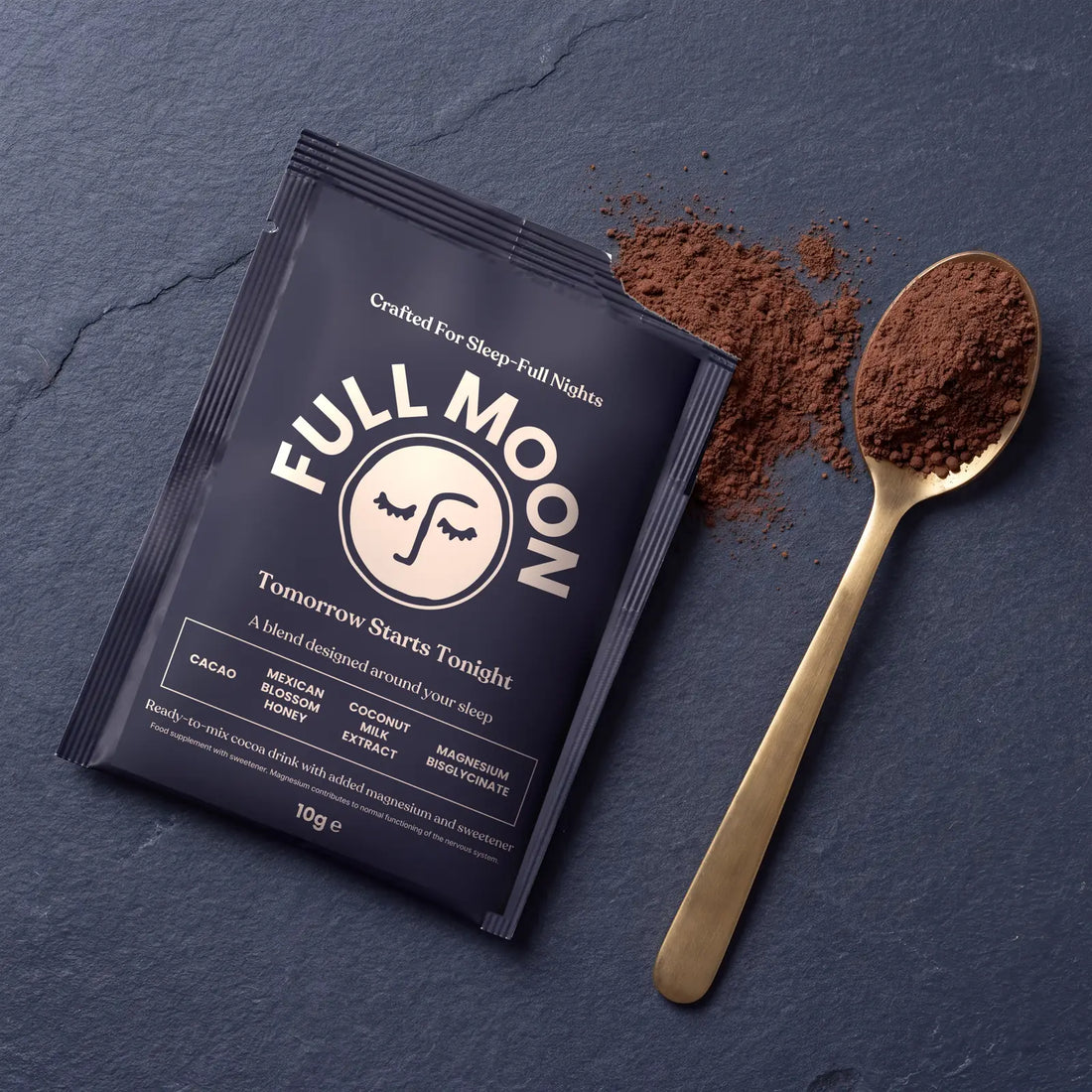 A Full Moon sachet next to cacao powder and a gold spoon